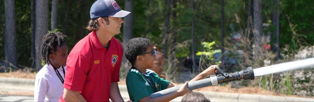 Captain Brian Belvins using fire hose with kids