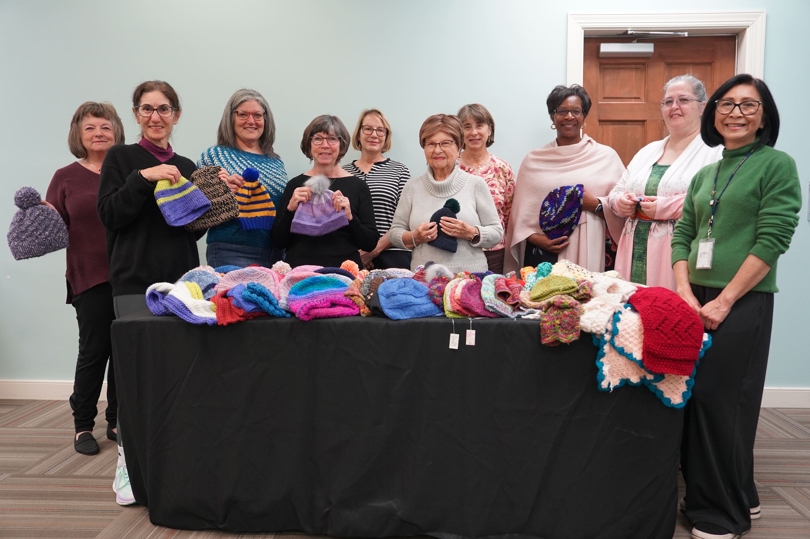 Group photo of Knit Night attendees holding donations