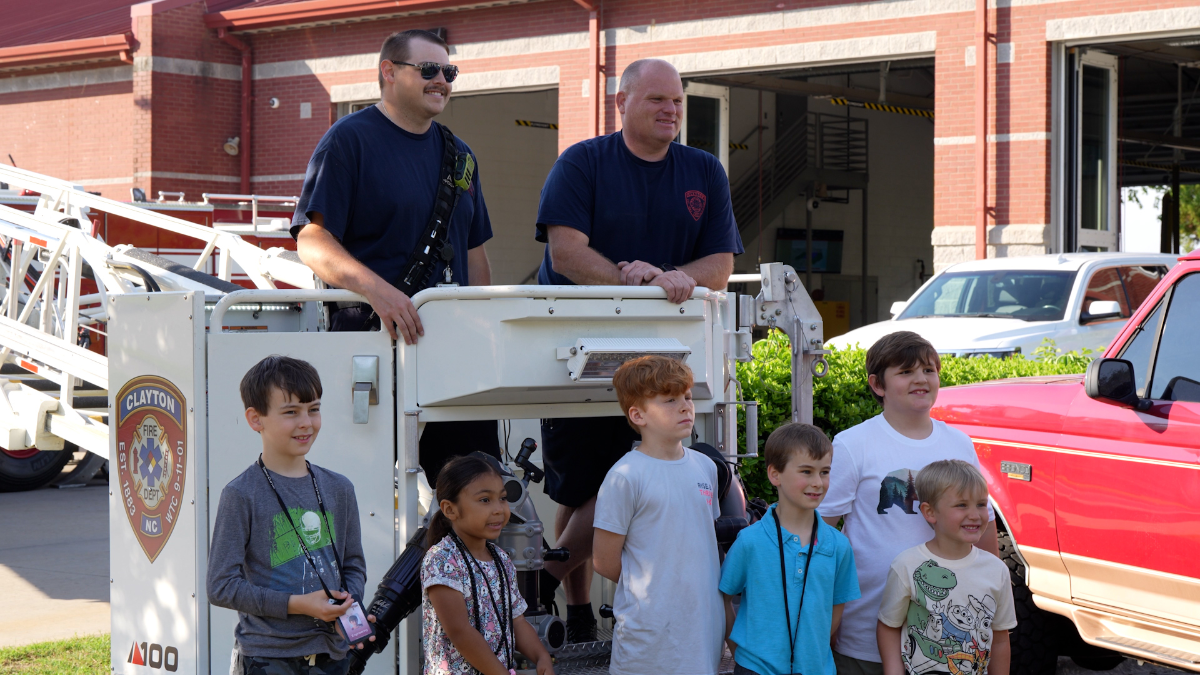 kids pose with firefighters in front of firetruck