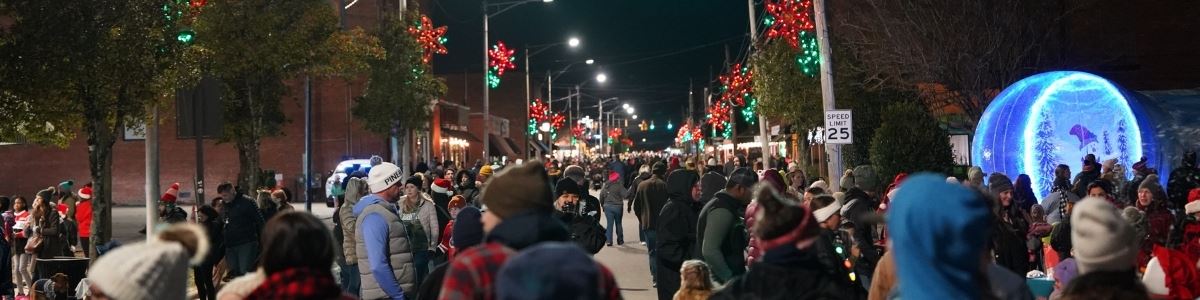 large crowd of people walk Clayton Main Street in winter attire