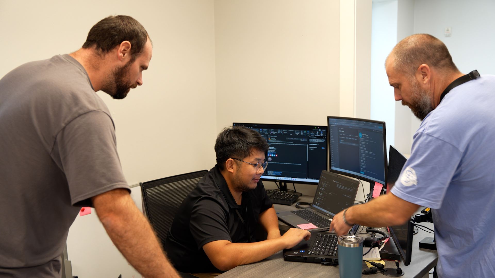 3 Clayton IT Department members gather around a computer